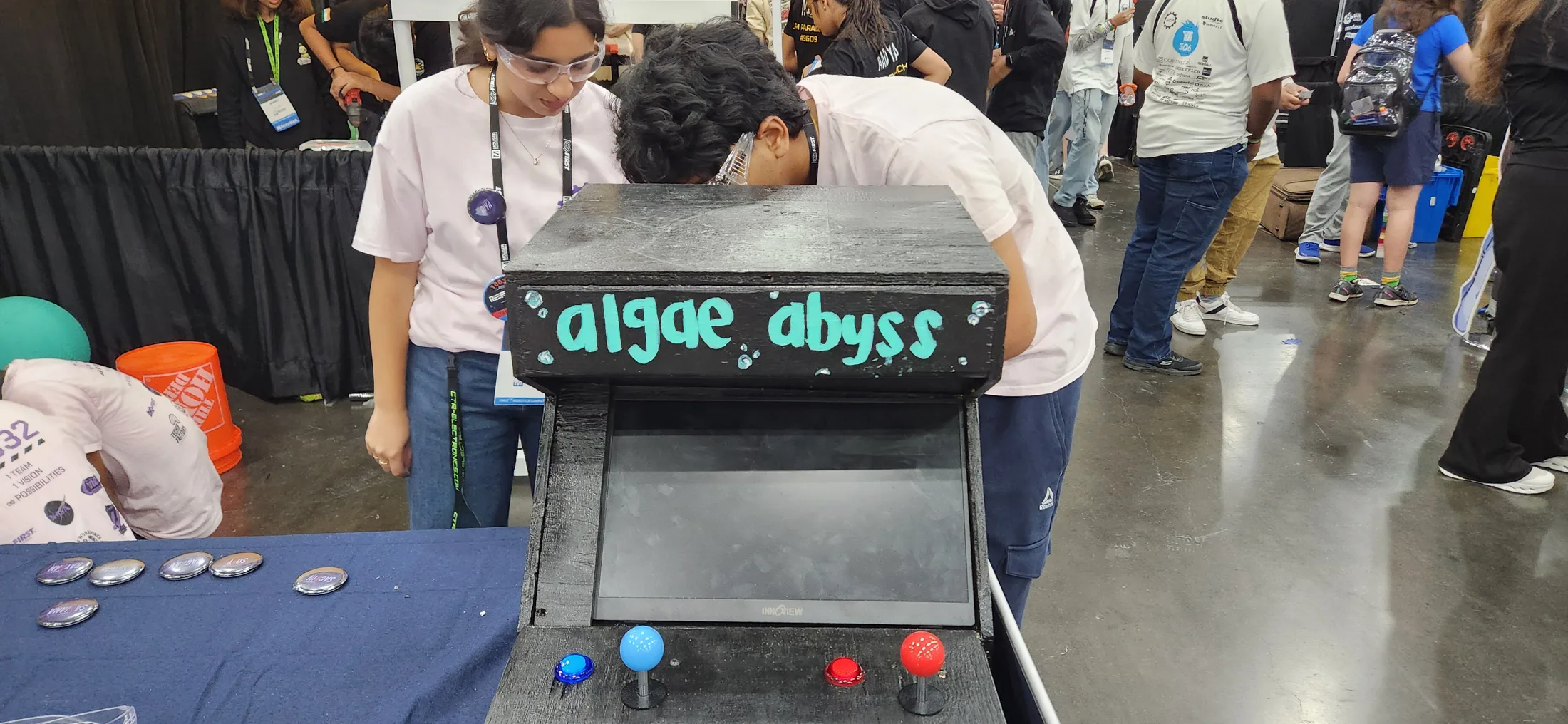 Students playing the Algae Abyss arcade cabinet at a competition