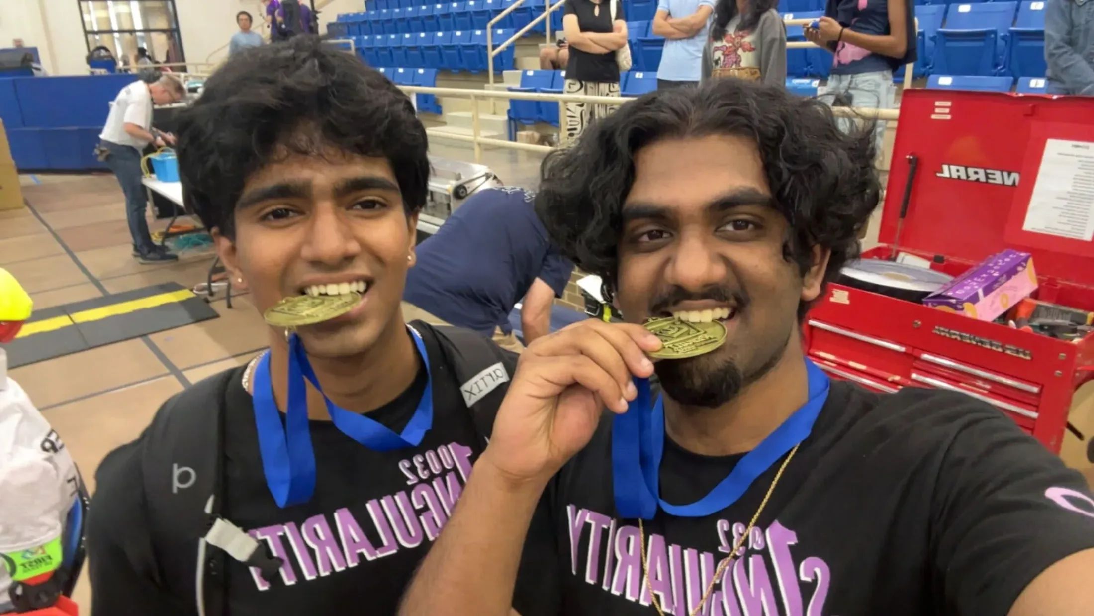 Two members biting their winner medals in the stands
