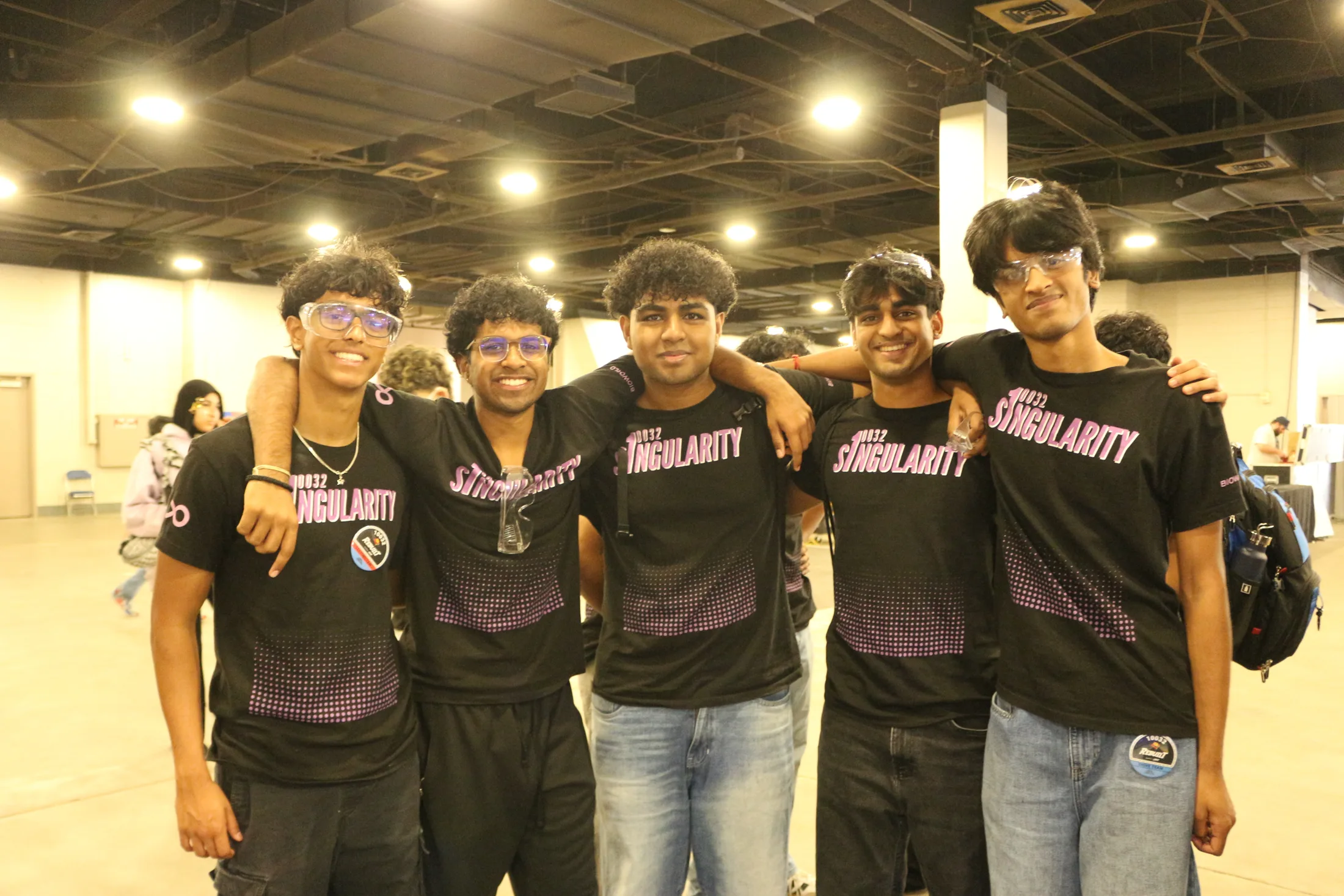 Five students arm-in-arm in black Singularity shirts in an arena hall