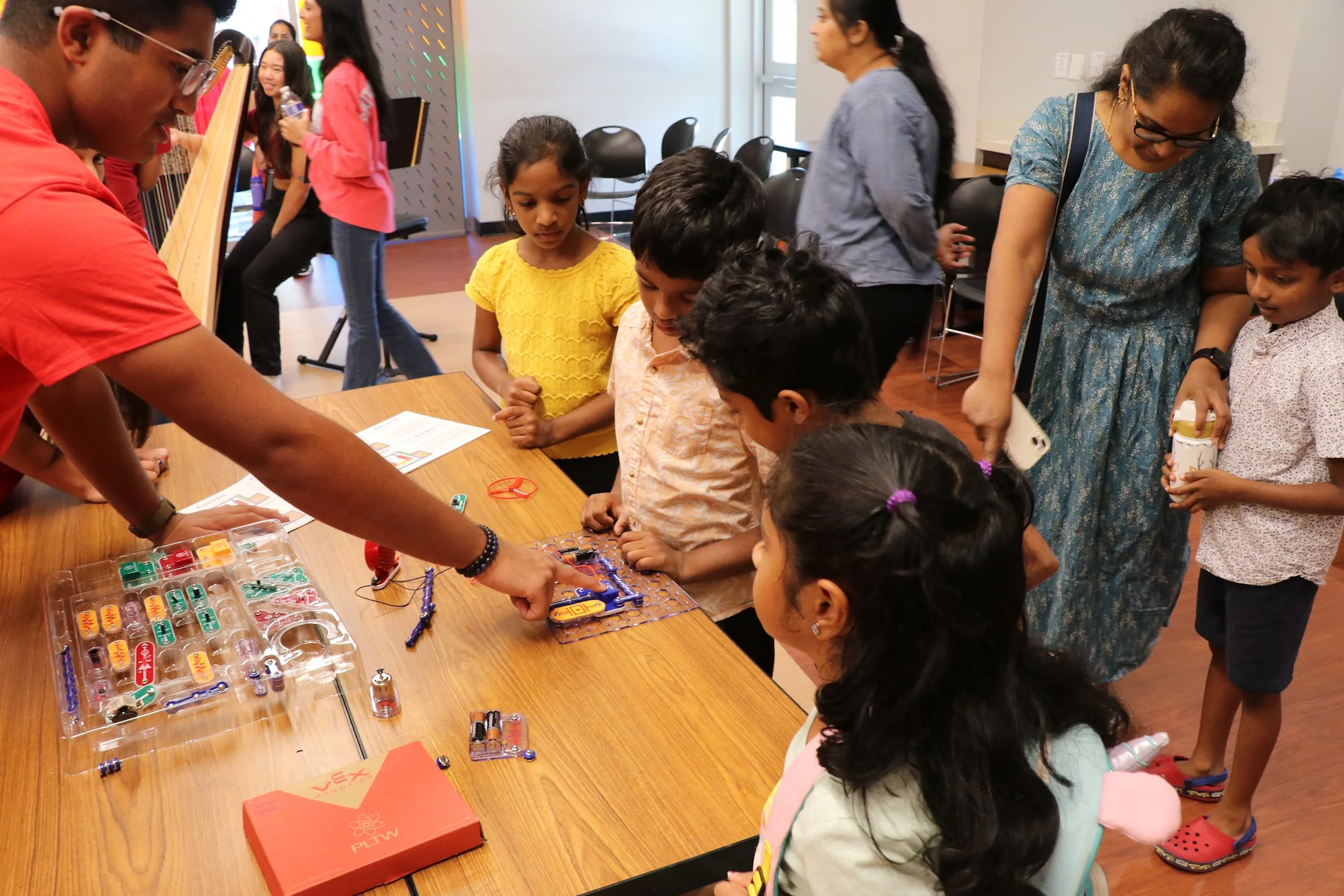 Kids at the circuit table with a Singularity volunteer